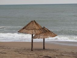 two thatched umbrellas on the beach on the ocean