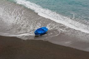 blue rowing boat on beach at surf line