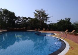 sun loungers by the pool with blue water