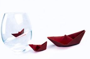 Red paper boats with one boat inside the vase with water