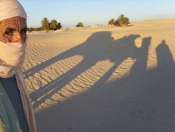 shadows from people and camel in the desert of tunisia