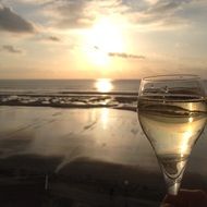 champagne in glass in front of beach at sunset