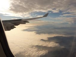 wing of aircraft above and beneath clouds