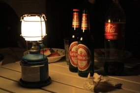 beer, coca cola and kerosene lamp on the table in the camping