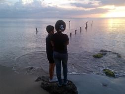 children watch the sunset on the beach