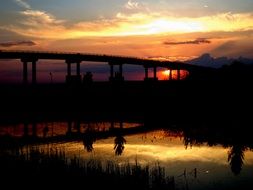 silhouette of the bridge in the rays of colorful sunset