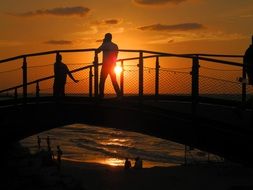 silhouette of people on a bridge at sunset