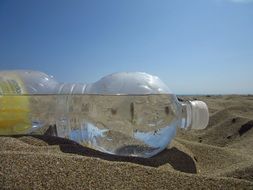 plastic water bottle on a sandy beach close up