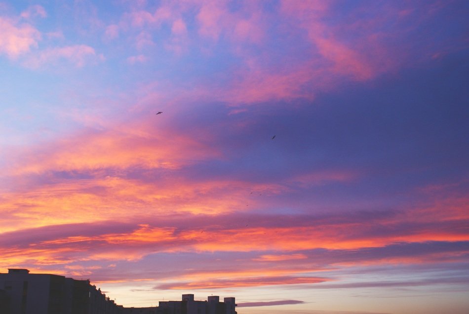 pink clouds in the sky during sunset over the hill