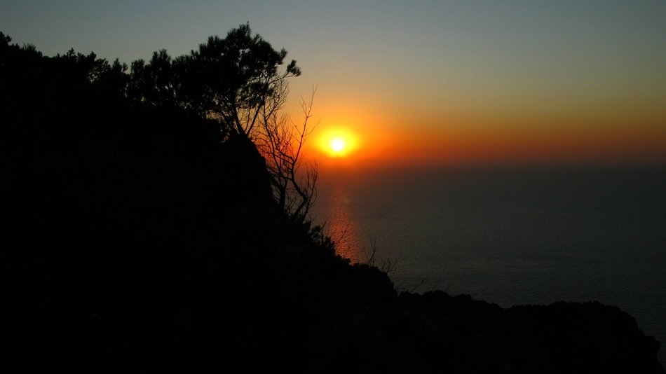 orange evening sky over the silhouettes of the coast in summer