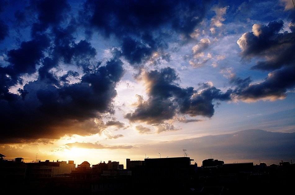 sunset behind the clouds over buildings