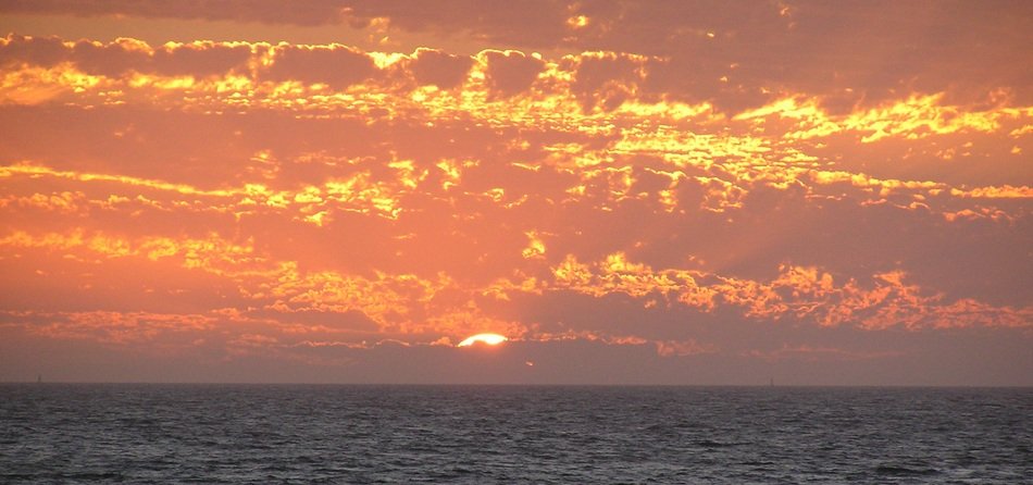 Landscape of bright orange sky over the ocean in Spain