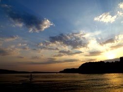 sunset above coastline at calm water