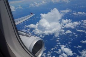 View aircraft engine and white clouds in blue sky from an airplane window