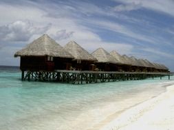 row of bungalows on water at beach, maldives, mirihi