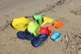 colorful beach toys and blue sandals on sand