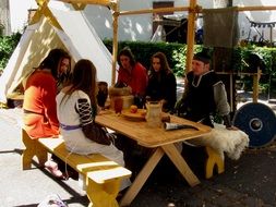 young people in historical costumes in camp on medieval festival