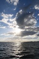 the sun behind the clouds over the sea