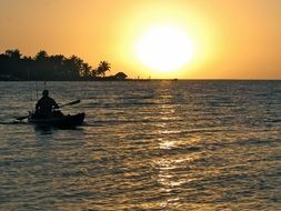 silhouette of a man in a boat on a background of orange sunset