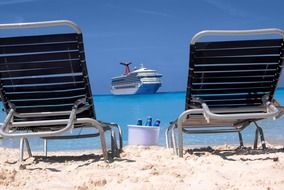 the Carnival Triumph cruise ship on sea in front of two chairs on beach, Bahamas, half moon cay