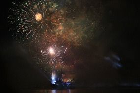 fireworks above navy ship on ocean at night