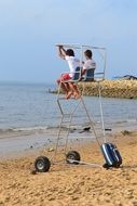 two men on rescue service tower over beach
