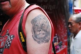 tattooed in the form of a lion on a manâs shoulder