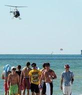 a group of students on the background of the sea and a flying helicopter