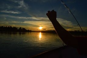 fishman fishing in boat sunset view