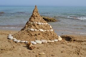 sandcastle at ocean beach with stones