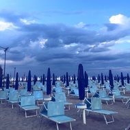 sun beds and umbrellas on the beach under a rainy sky