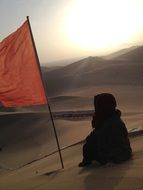 man and red flag in the desert