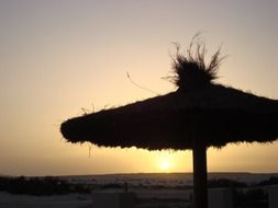 sunset on the background of an umbrella on the beach