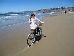 girl riding a bicycle along the beach