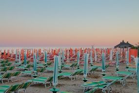 many green sun loungers on the beach at sunset