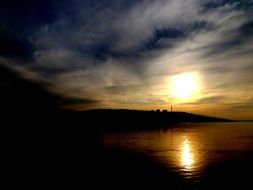 sunset is reflected in the water in the dark twilight