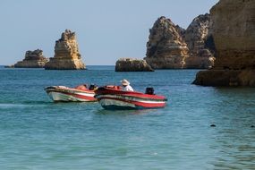 fishermen in boats in the ocean near the rocks