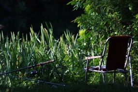 night fishing, chair and rods on bank of lake