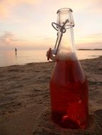 a bottle of drink in the sand on the beach