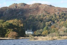 white old castle in a green forest by the lake