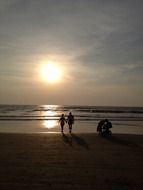 silhouettes of mother and baby watching sunset at beach