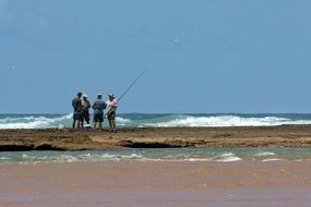 four men on sand at surf line, south africa