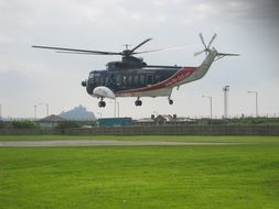 passenger helicopter above green lawn, uk, isles of scilly