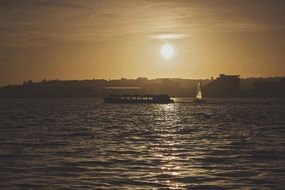 ship and sailboat on sunset background