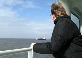 man looks at the sea at the side of the ship