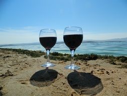 two glasses of wine on a sandy beach