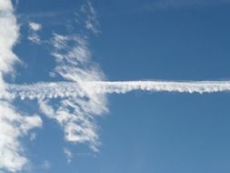 trail from the plane in the blue sky with clouds