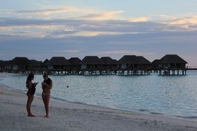 girls stand on the beach in the maldives