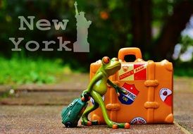 statuette of a frog with a bag near a suitcase in new york