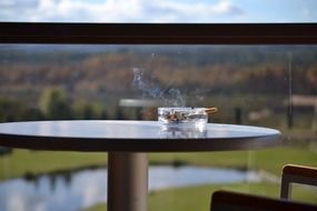 table, and an ashtray with a cigarette on the balcony